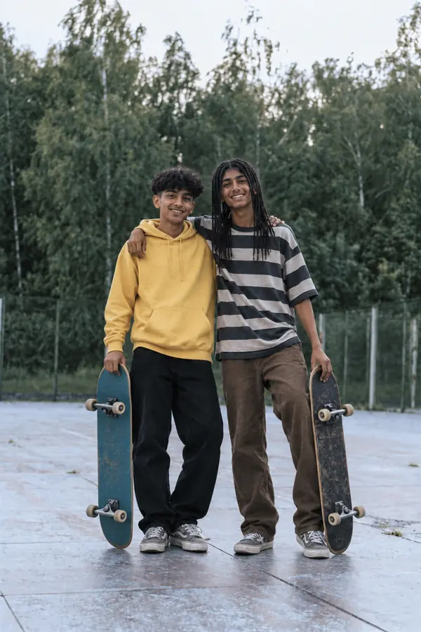 Two teenage friends holding skateboards at a skatepark